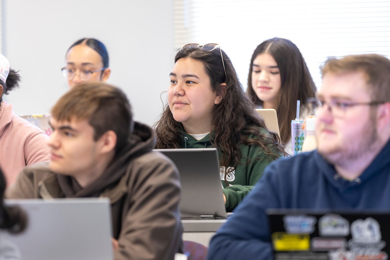 Illinois Wesleyan students listening attentively in a classroom with laptops open