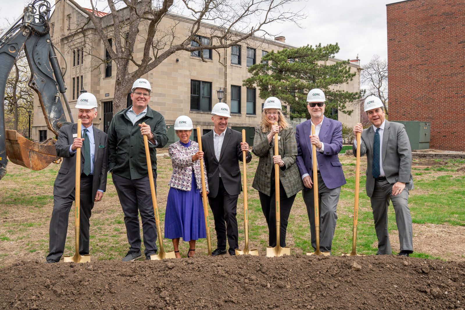 University leaders and donors in hard hats holding gold shovels at a campus groundbreaking